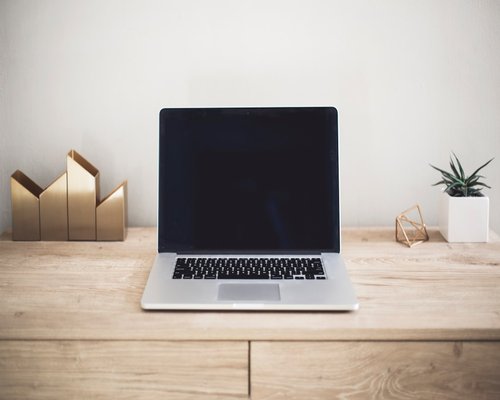 A laptop computer displaying text documents at a proper viewing distance on a clean minimalist wooden desk setup